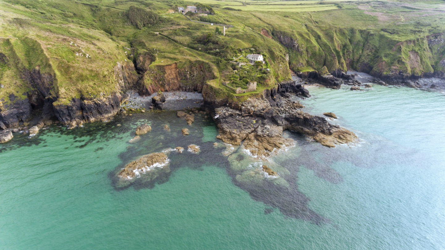 Aerial view of Cornish coastline with high cliffs, rocky shore, stone beaches, coastal footpaths near St Ives, Cornwall, south west England, on a cloudy summer day .