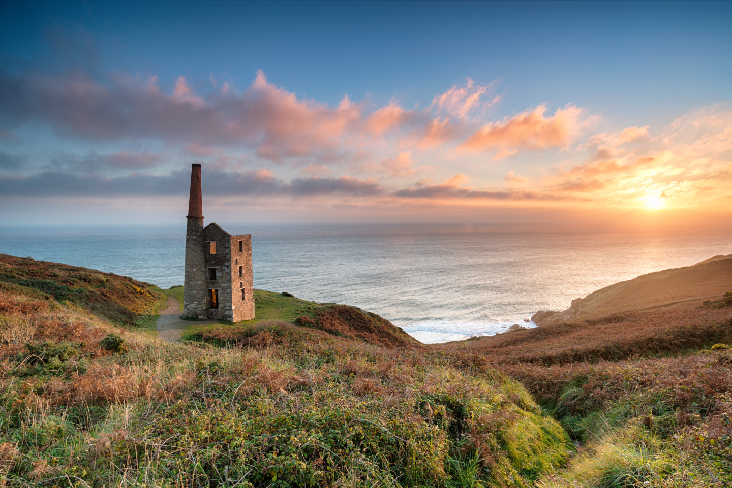 Stunning sunset on the South West Coast Path as it passes the ruins of the Wheal Prosper engine house on cliffs at Rinsey Head near Porthleven in Cornwall