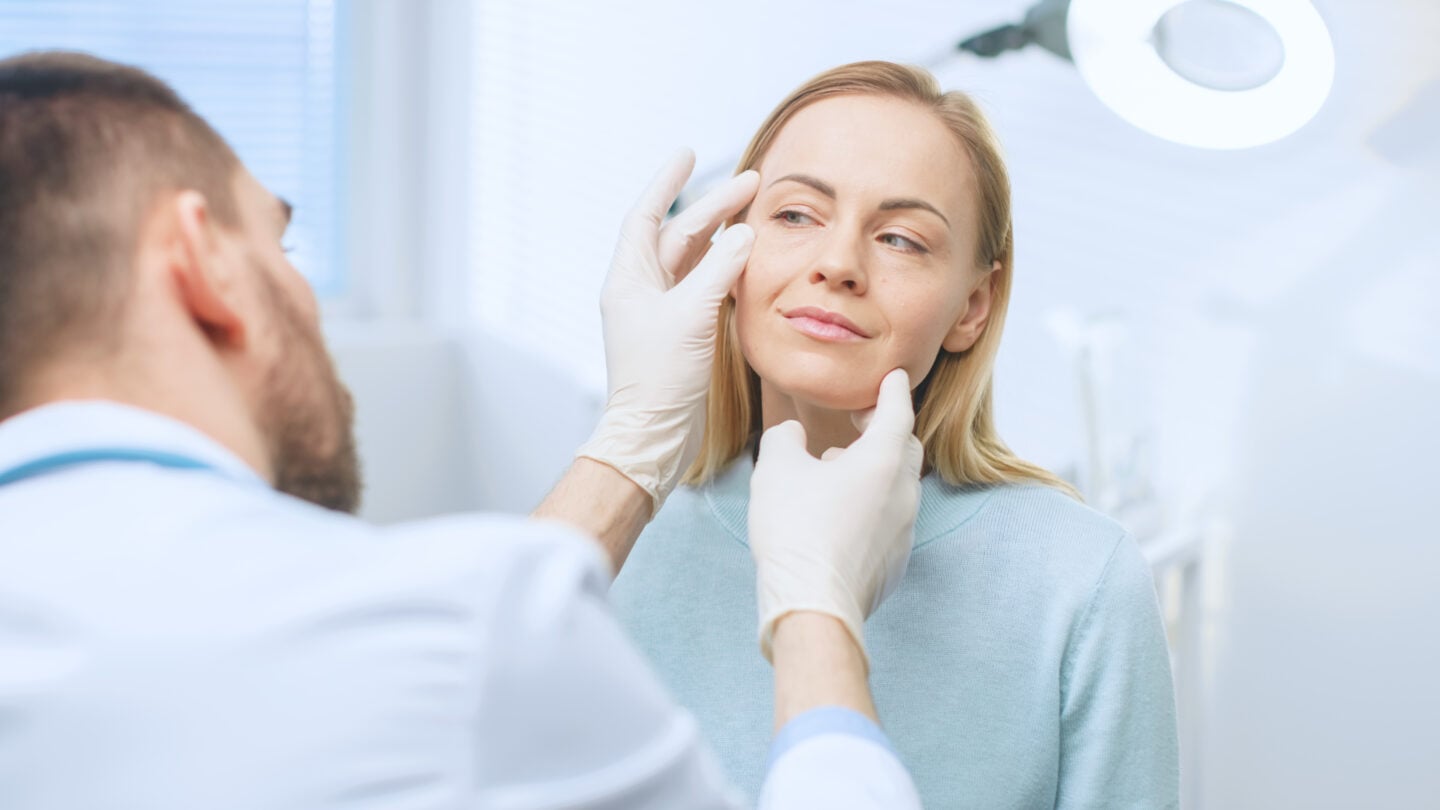 Plastic / Cosmetic Surgeon Examines Woman's Face