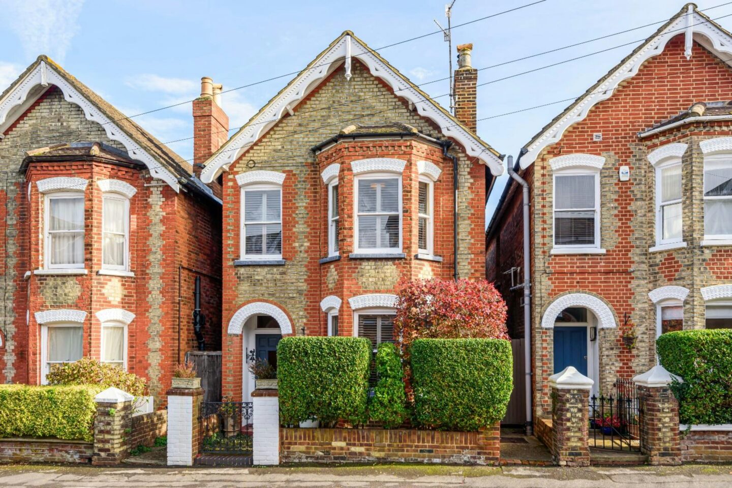 Row of traditional British terraced houses with brick façades and tidy front gardens.