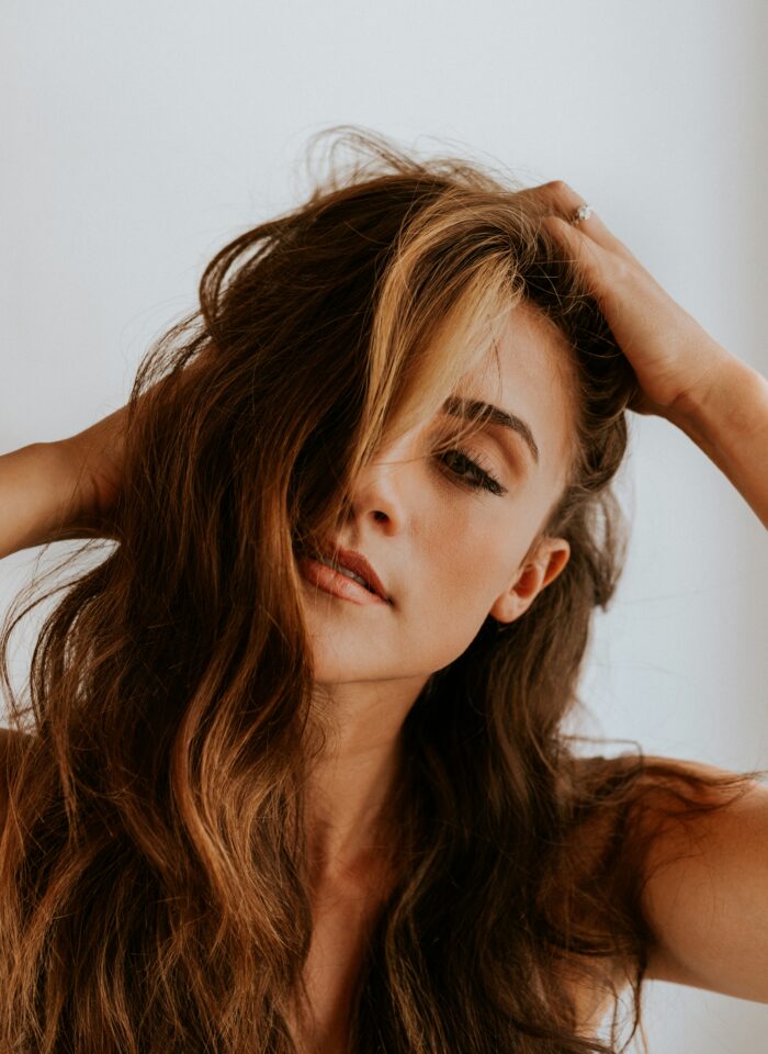 Woman with voluminous wavy hair running hands through her hair in a natural beauty portrait