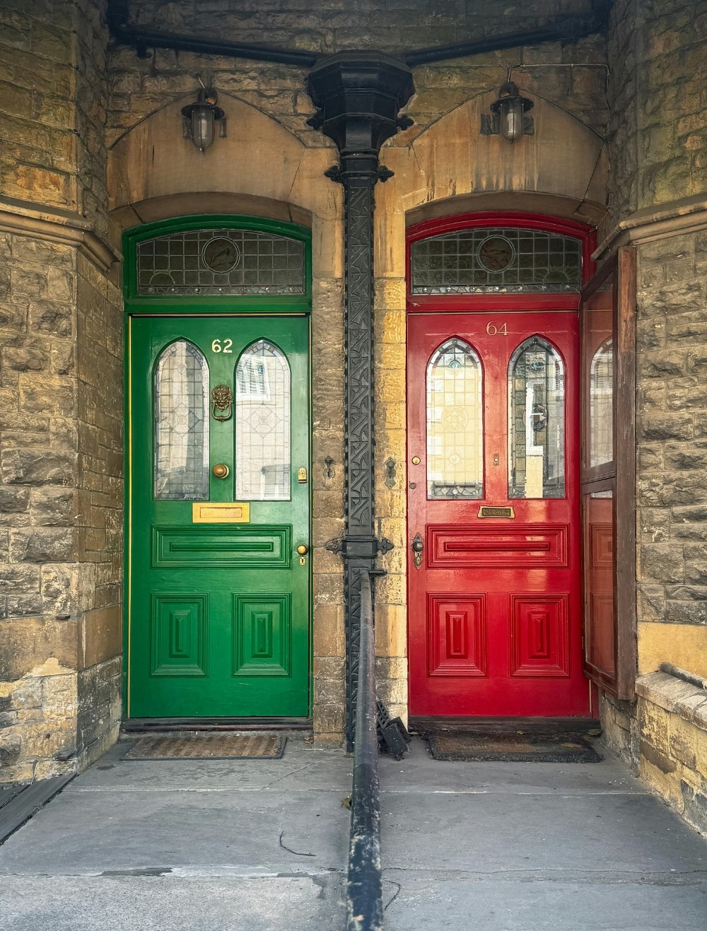 Two colourful front doors side by side in a stone building.