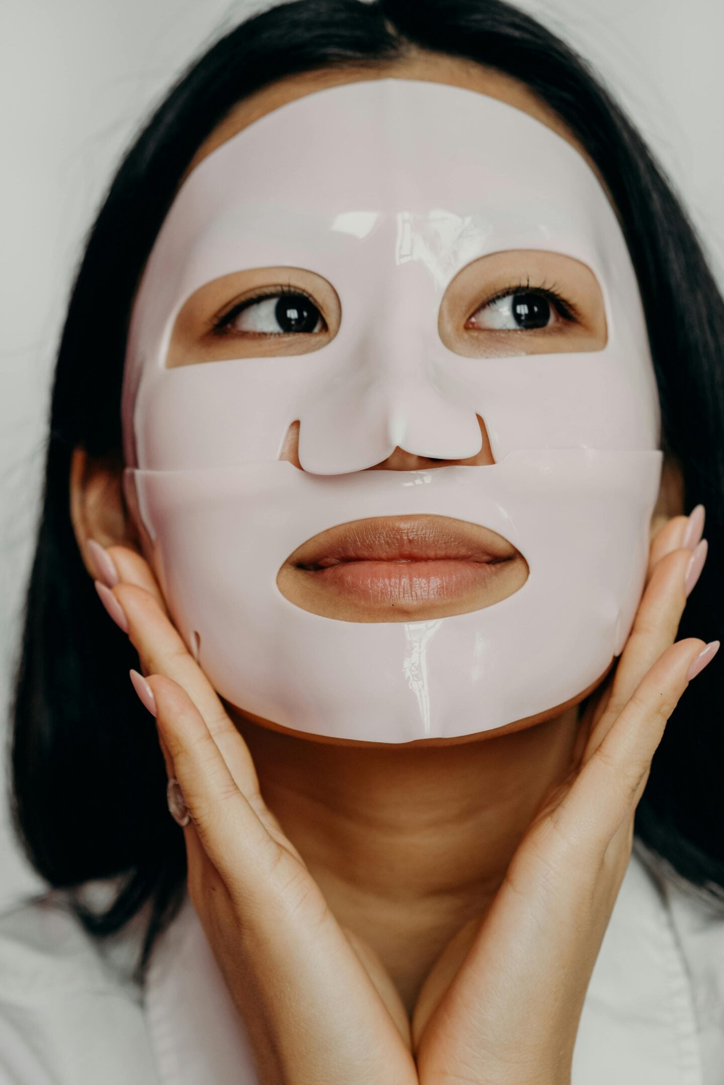 Woman wearing a glossy pink Korean sheet mask as part of a skincare routine