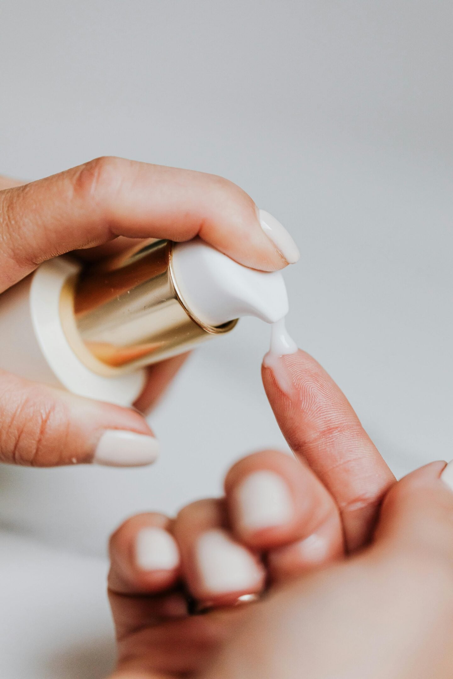 Close-up of hands applying moisturizing serum from a pump bottle, step in Korean skincare