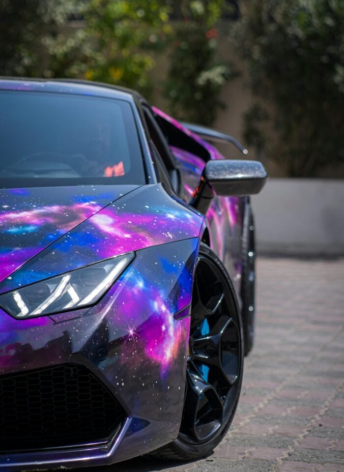 Close-up of a sports car with a vibrant galaxy-themed vehicle wrap, showcasing a custom vinyl design.