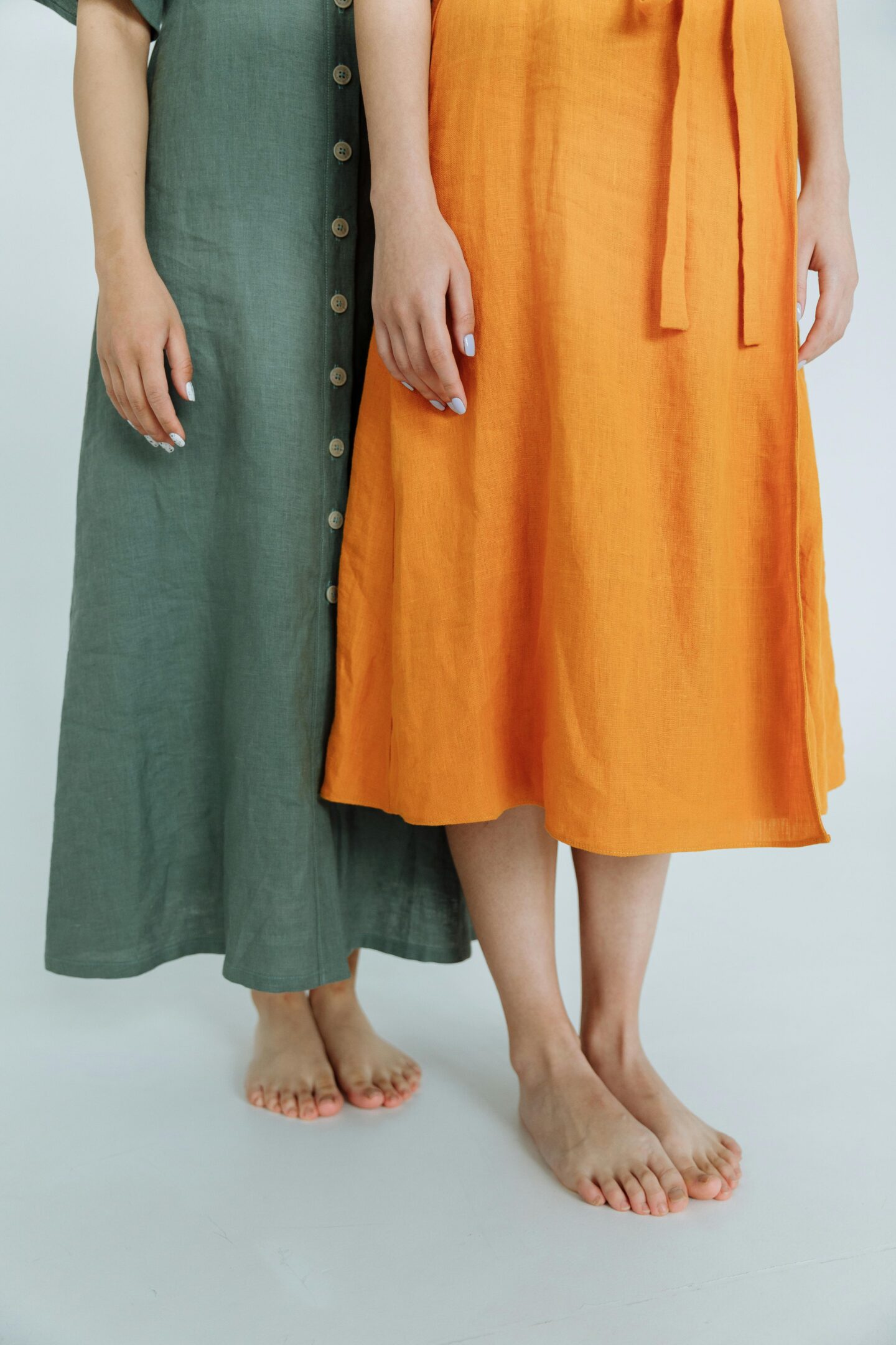 Minimalist portrait of two women wearing colorful linen midi dresses, showcasing breathable summer fashion.