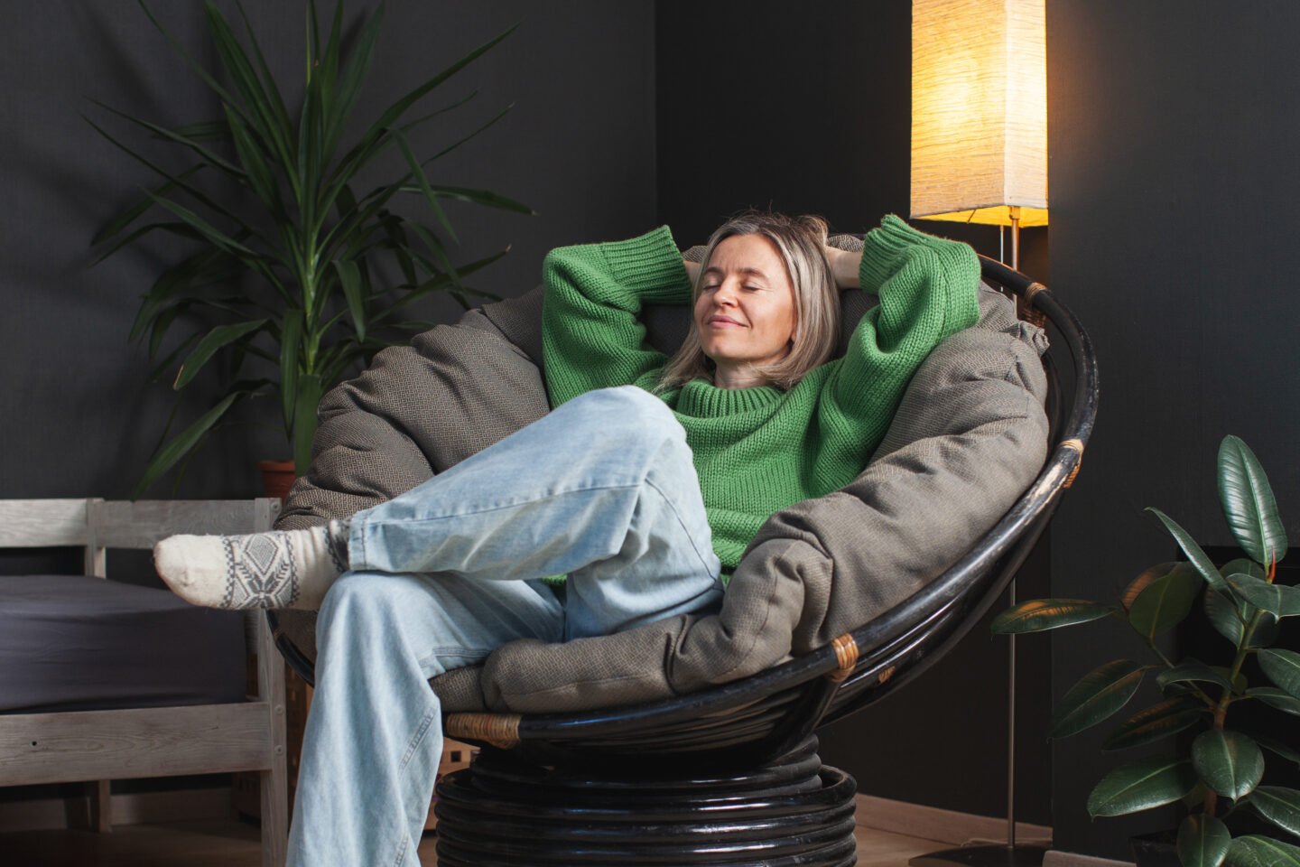 Modern boho interior with a woman lounging in a round chair, styled in a balanced space with symmetrical lighting and plant decor.