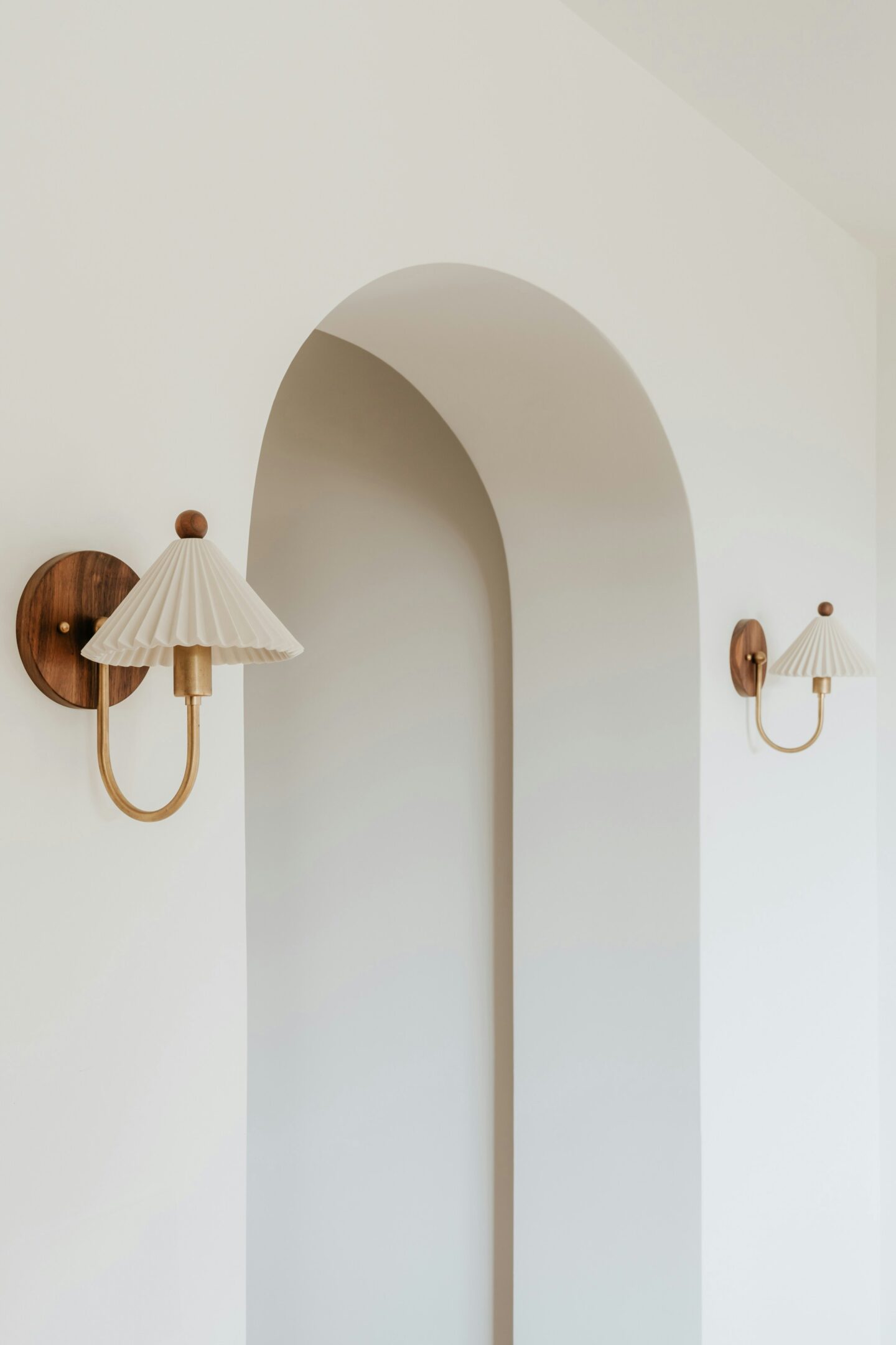 Minimalist hallway with symmetrical arched wall niches and evenly spaced matching wall light fixtures, creating a calm and elegant ambiance.