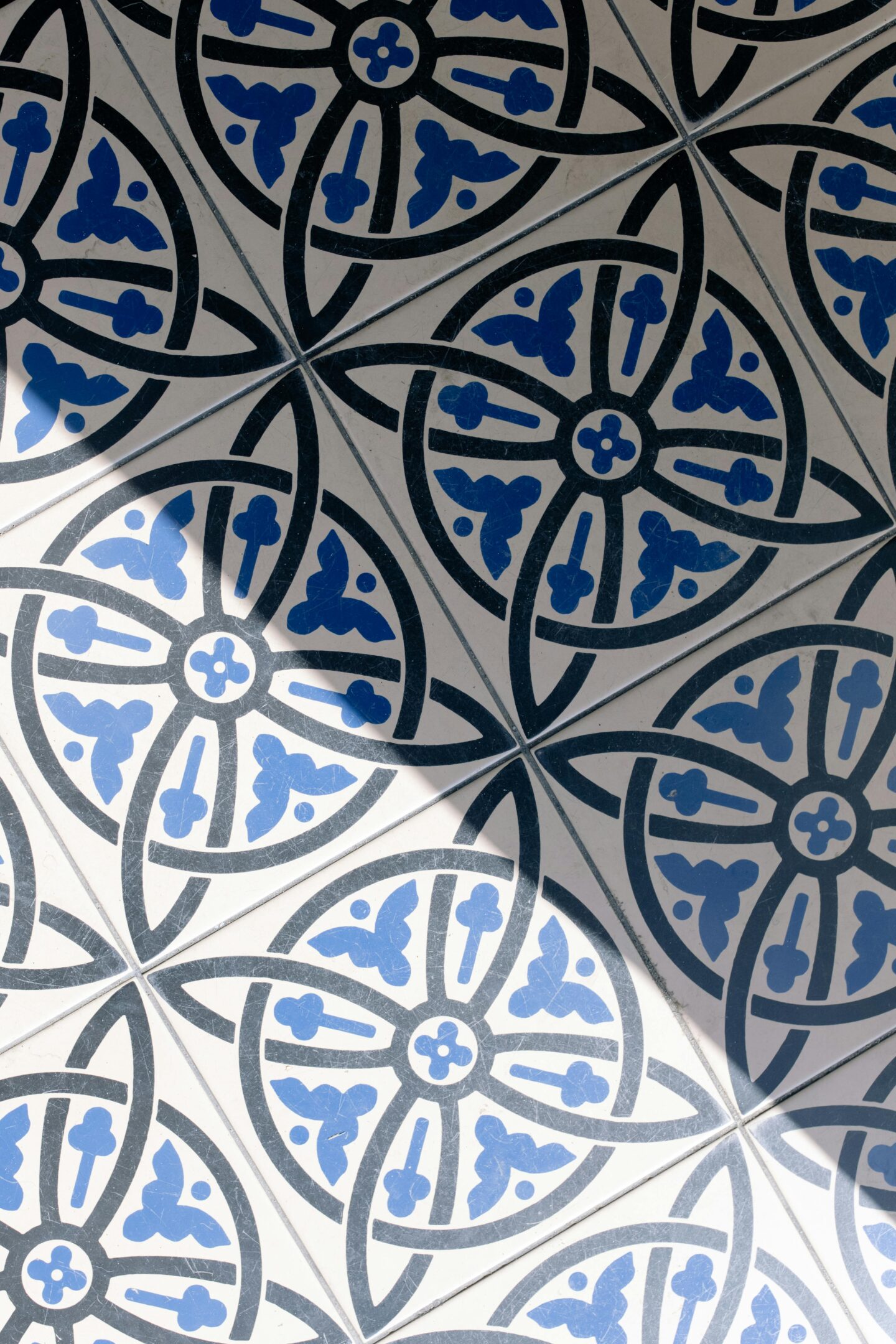 Symmetrical ceramic floor tiles with intricate blue and black geometric patterns, ideal for statement flooring in modern interiors.
