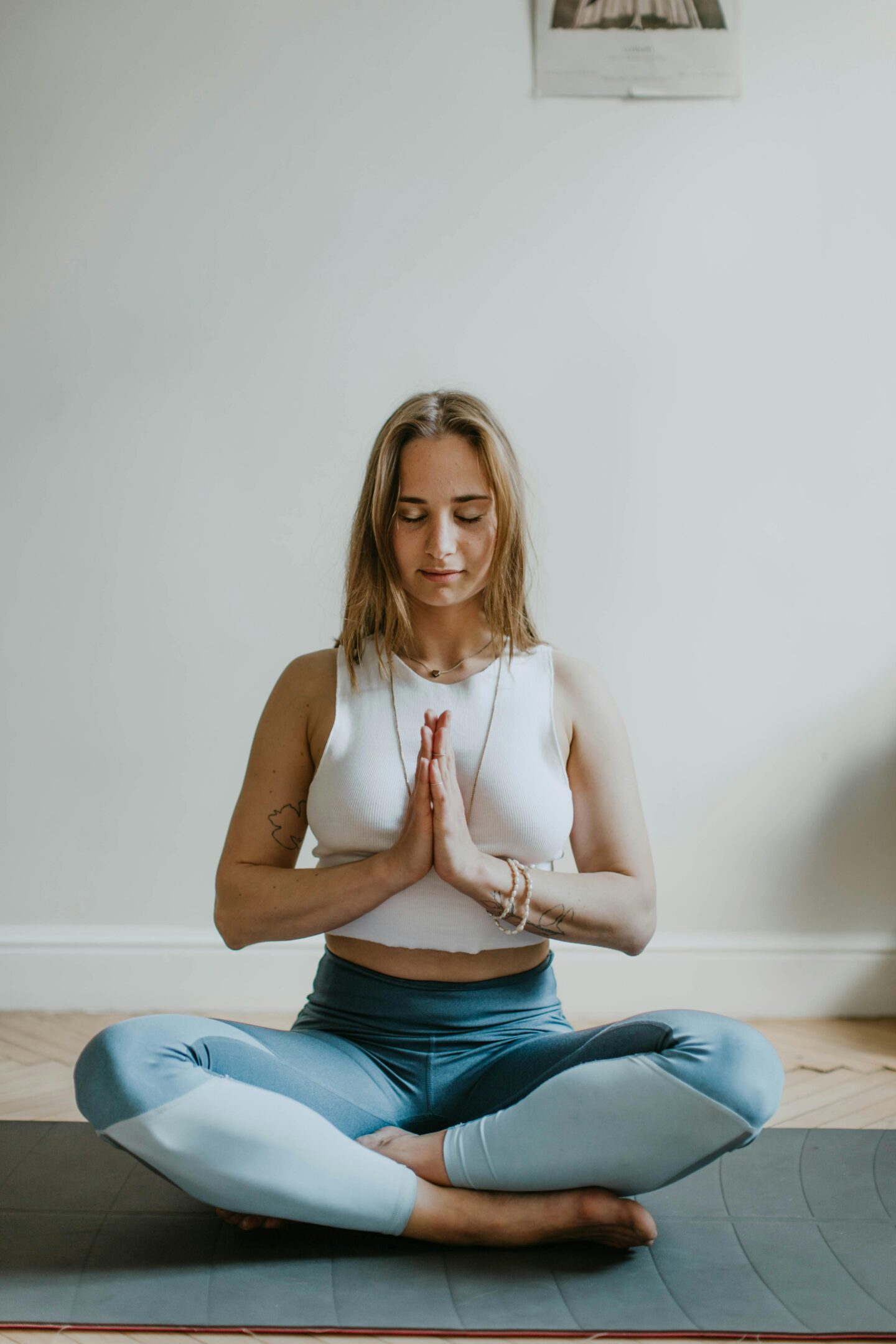 Young woman practicing mindfulness meditation in a serene home setting, promoting self-care and mental well-being through yoga.