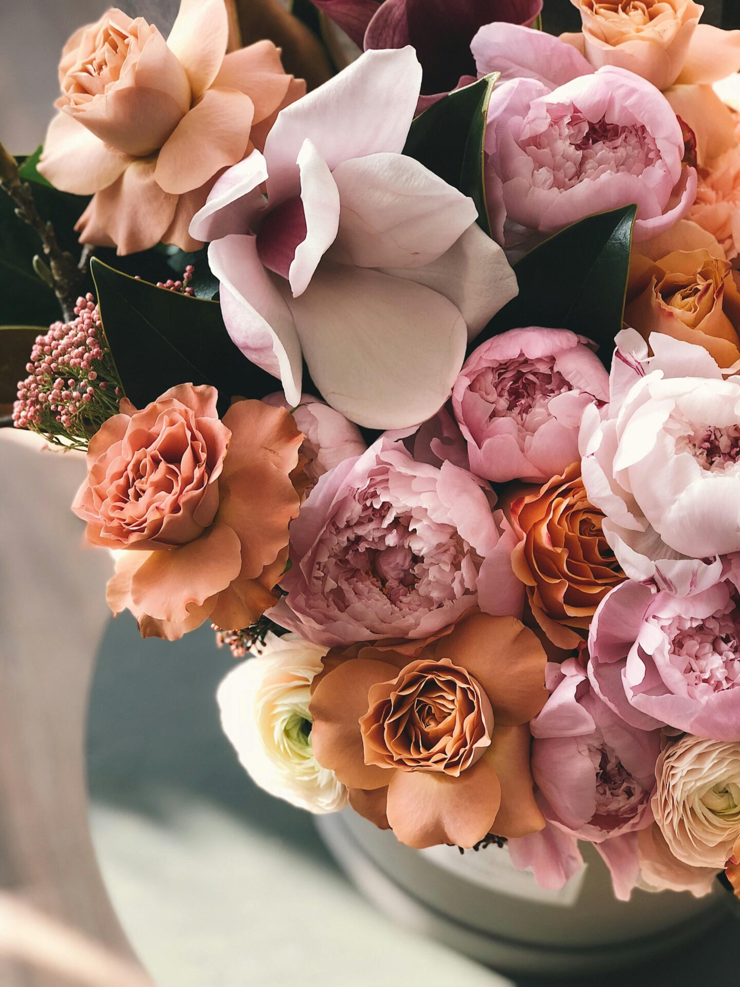 Elegant bouquet of pastel flowers including roses, peonies, and ranunculus in shades of peach, pink, and cream.