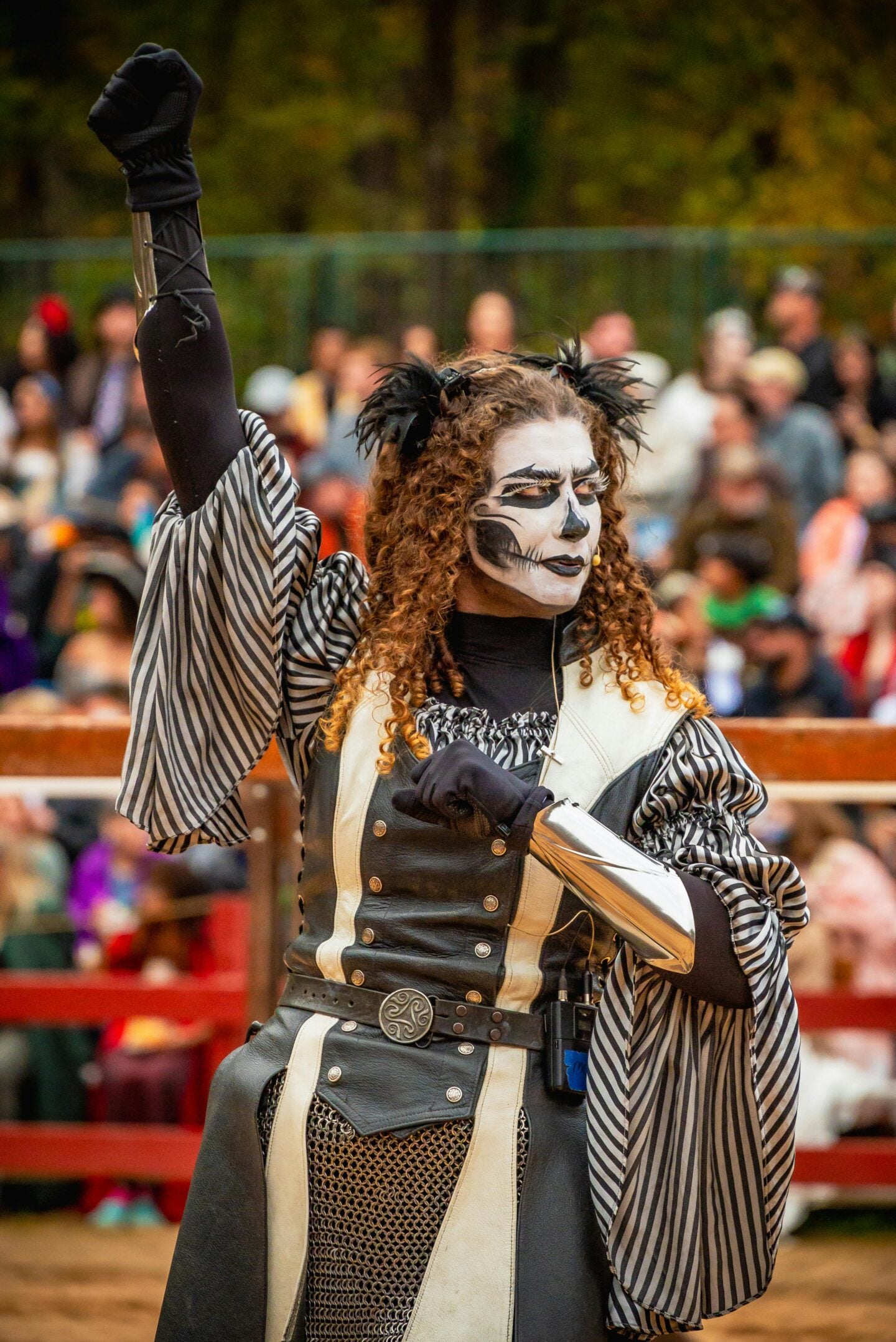Renaissance fair performer in striped costume and dramatic face paint