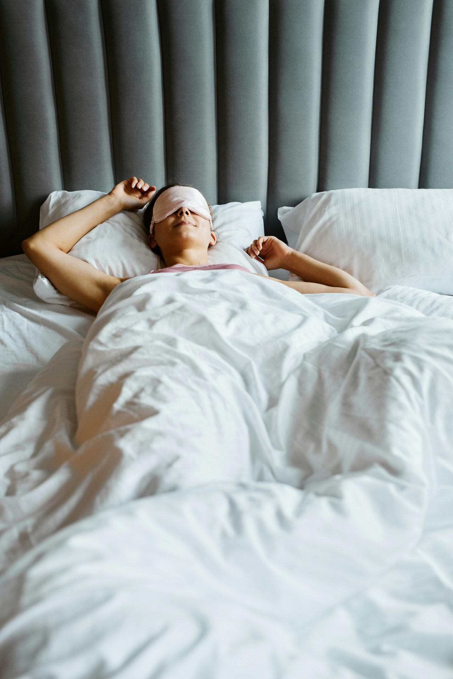 Woman resting in bed with an eye mask, practicing self-care through quality sleep.