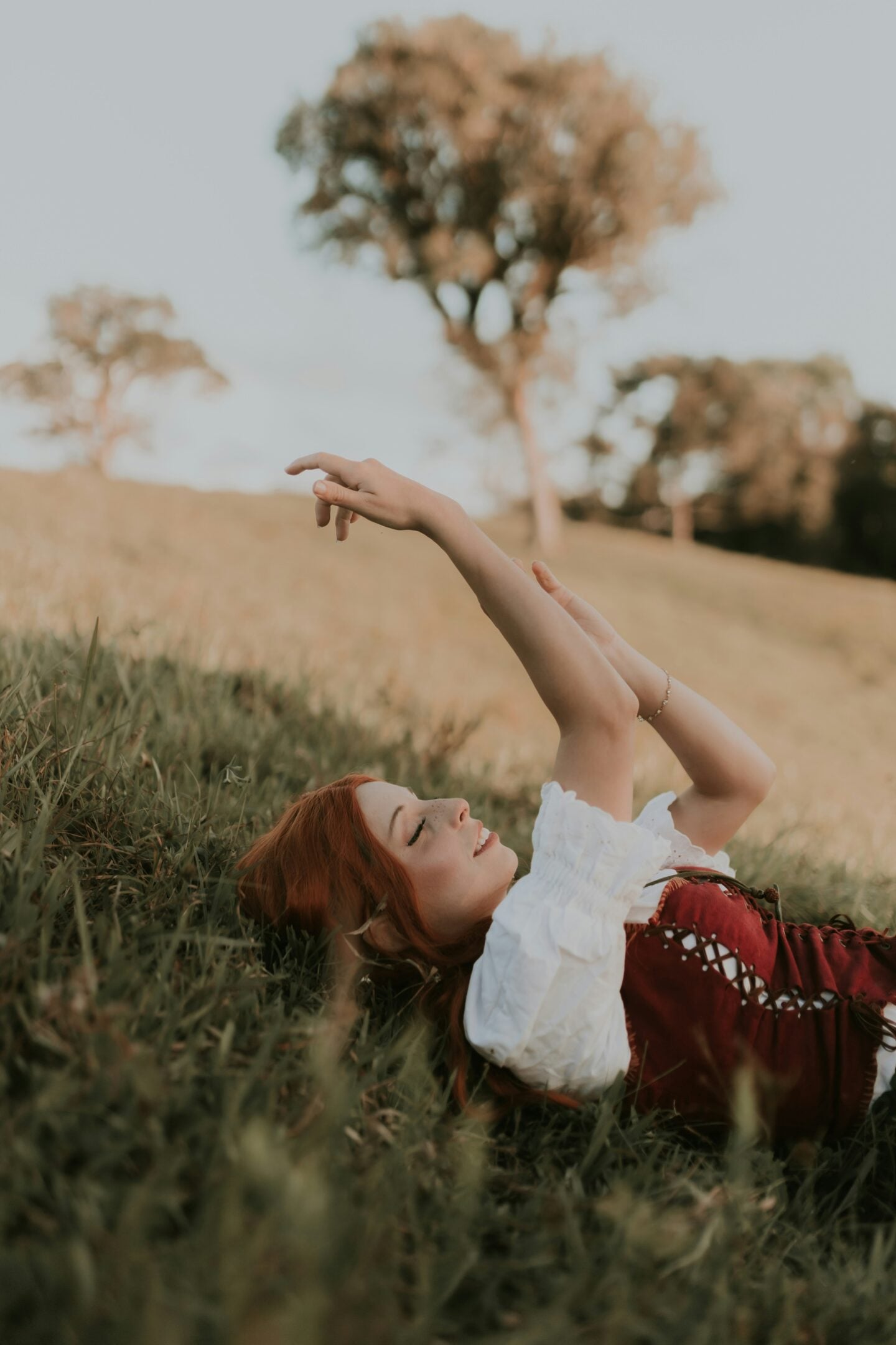 Woman in red corset dress relaxing on grass at Renaissance fair