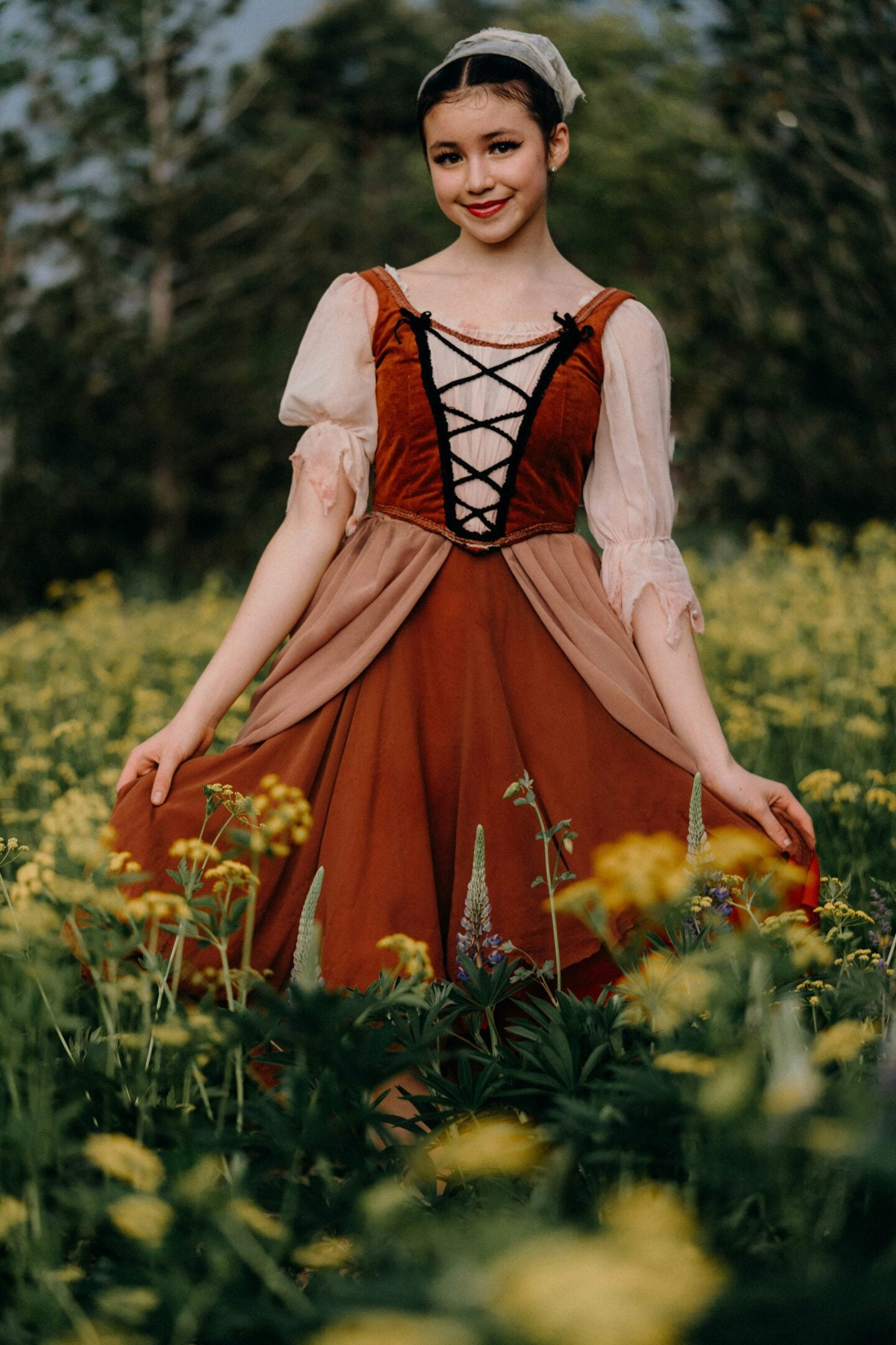 Young woman in Renaissance style red and beige dress posing in flower field