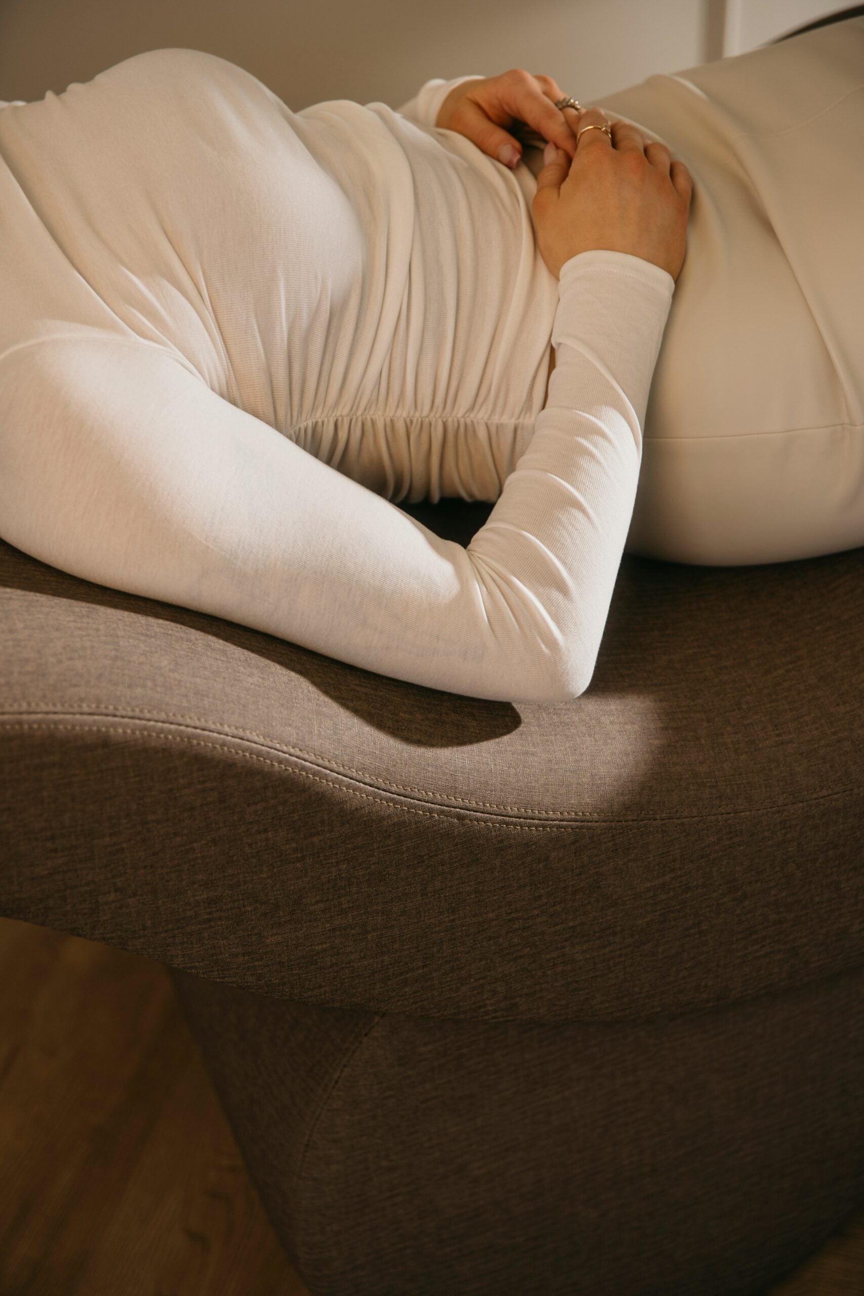 Close-up of a person resting on a softly curved, upholstered behavioral health lounge chair designed for safe and calming environments.