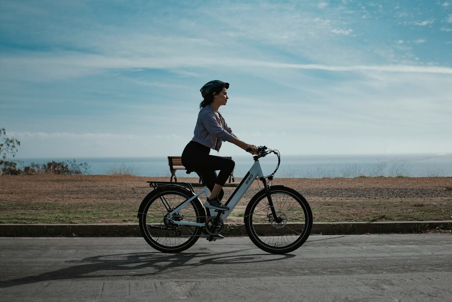 Woman riding a bicycle outdoors on a sunny day, promoting outdoor activity for better eye health.