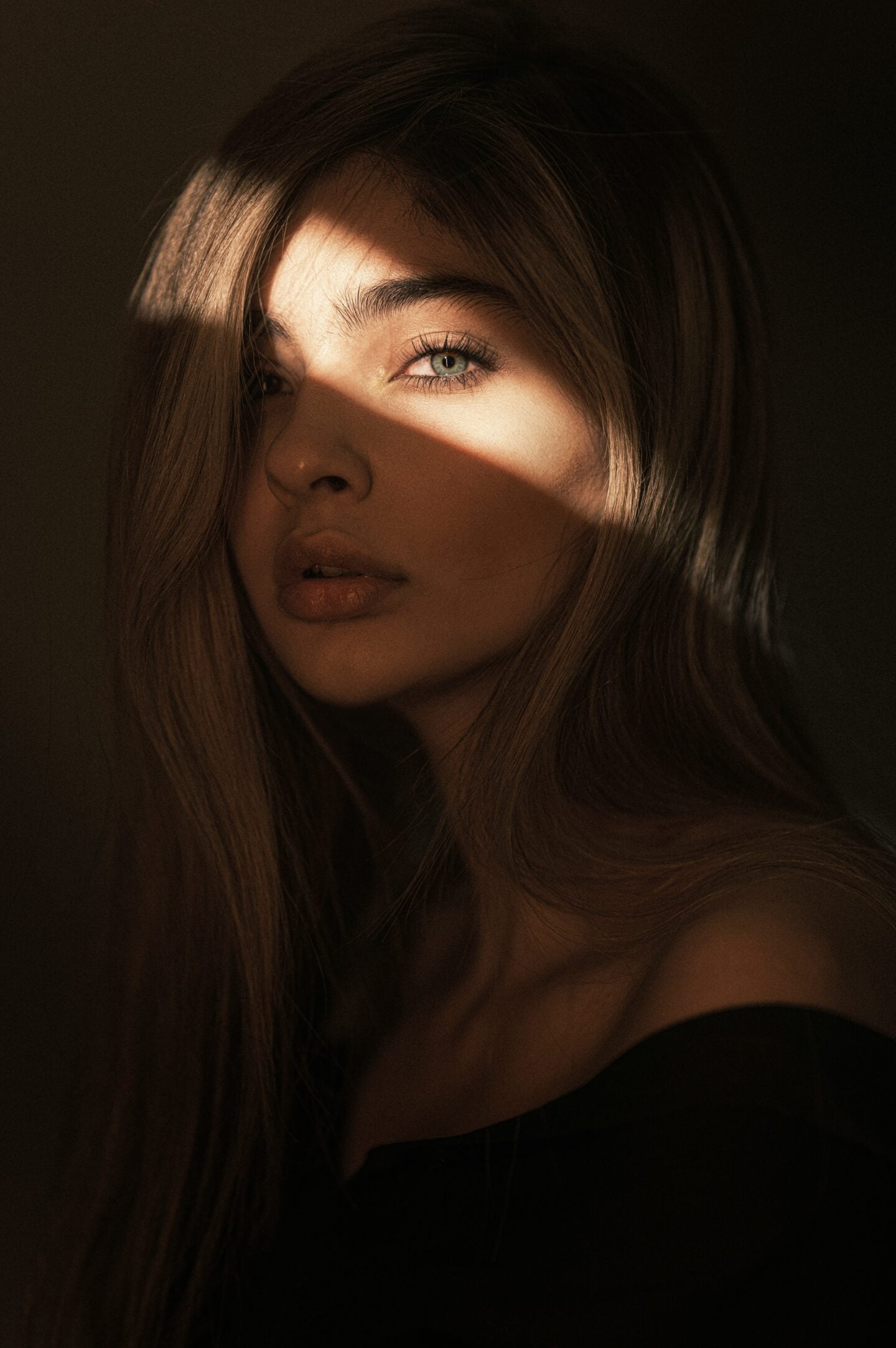 Portrait of a young woman in soft sunlight with light on her eyes.