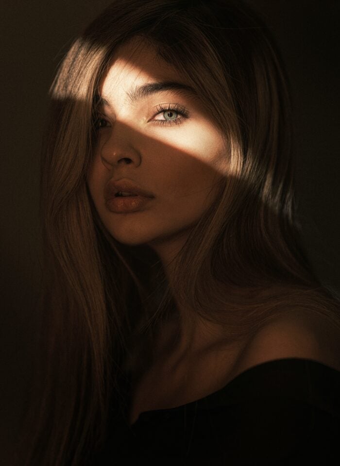 Portrait of a young woman in soft sunlight with light on her eyes.