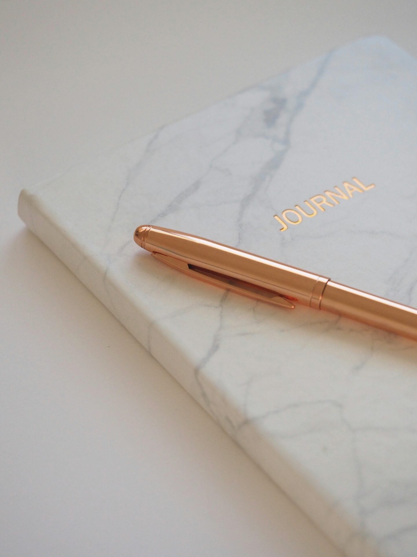 Marble-patterned journal with a gold pen resting on its cover, ready for evening journaling.