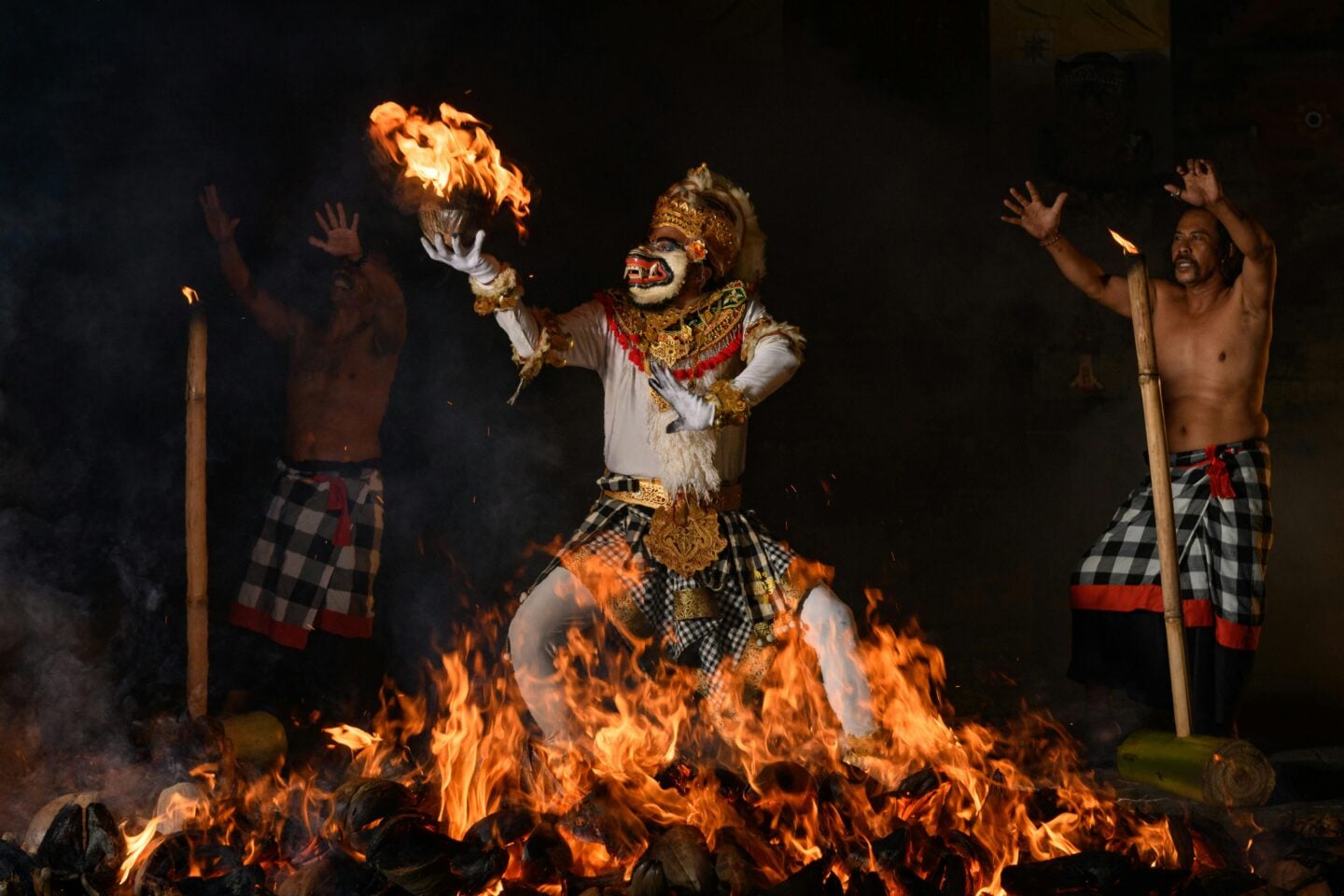 Traditional Balinese fire dance performance with a performer in costume holding a flaming object.