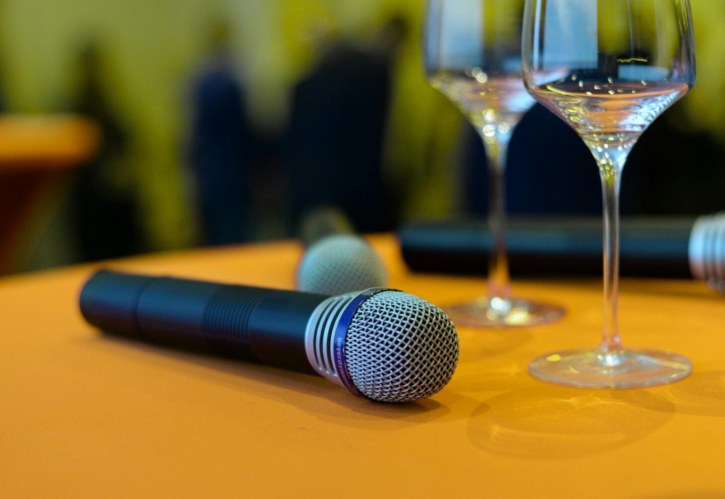 Close-up of two microphones lying on a table beside empty wine glasses.