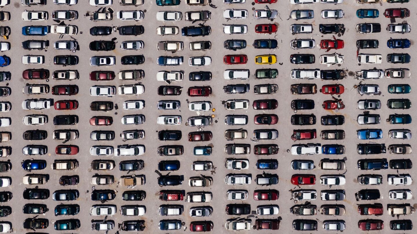 Aerial view of a large parking lot filled with rows of cars.