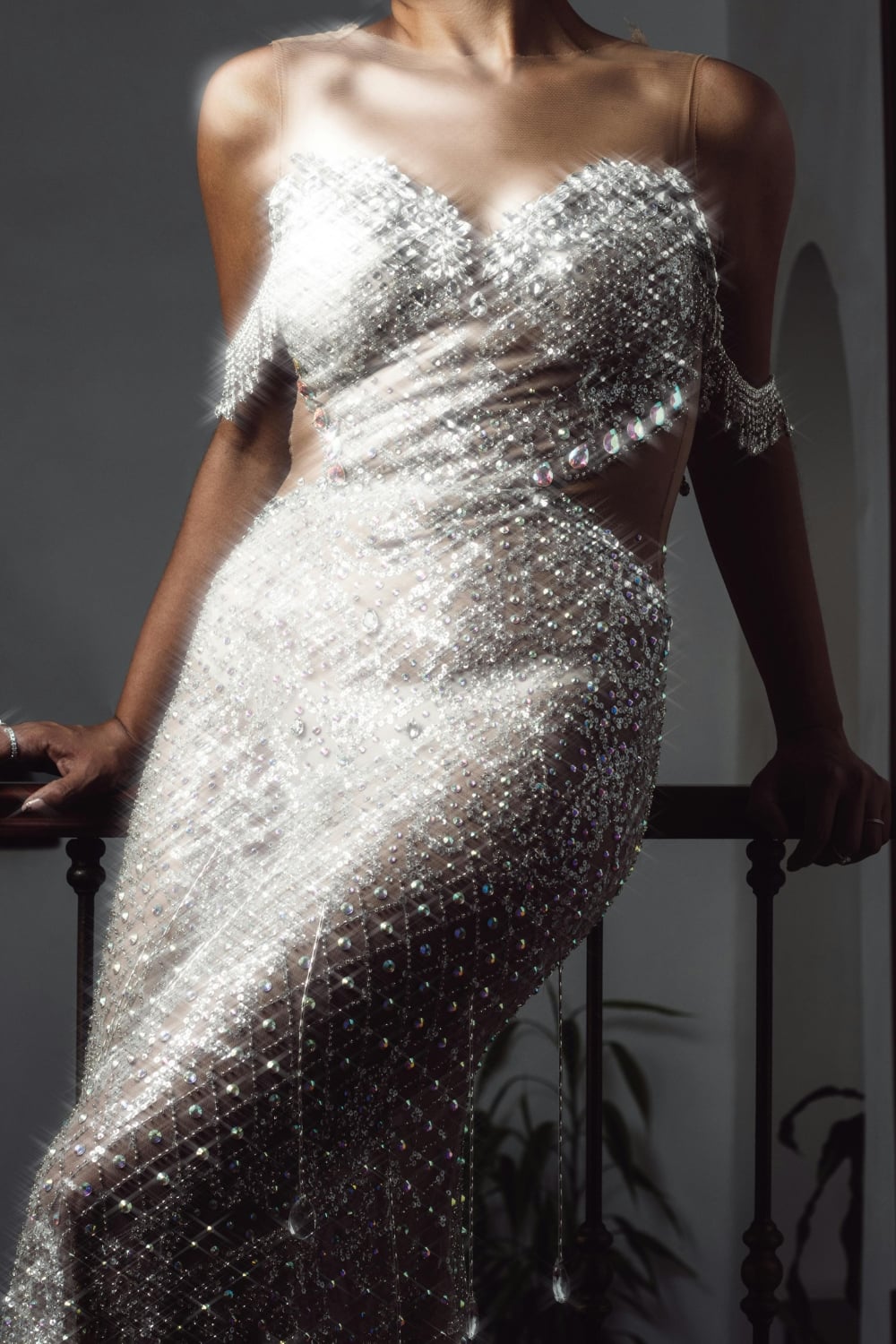 Close-up of an elegant evening gown shimmering with Swarovski sew-on stones, featuring a sheer bodice and densely beaded skirt that catches the light beautifully.