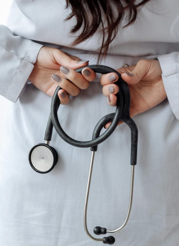 Close-up of a healthcare professional holding a black stethoscope while wearing a white coat, representing concierge medical services.