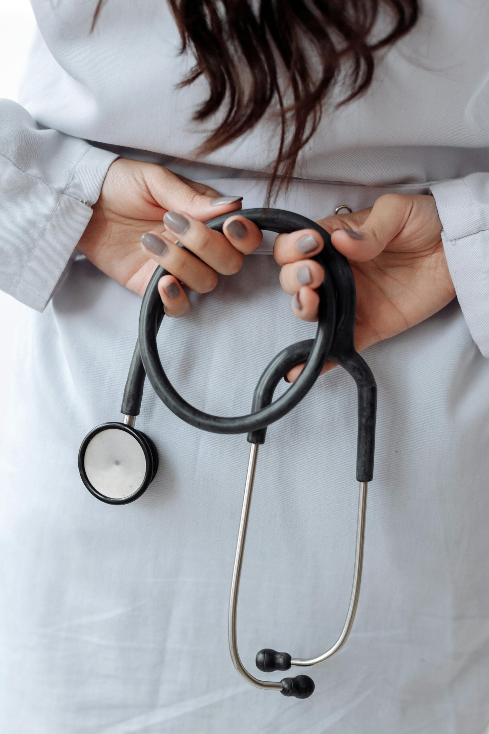 Close-up of a healthcare professional holding a black stethoscope while wearing a white coat, representing concierge medical services.