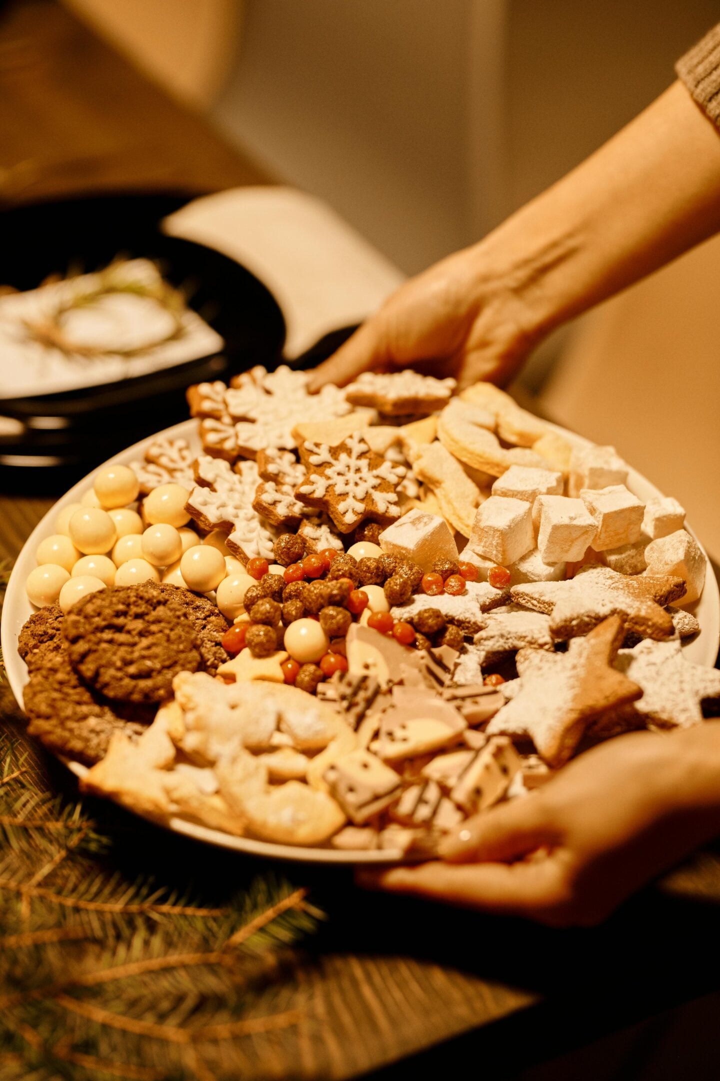 Plate full of assorted homemade Christmas cookies and sweets with festive decorations.
