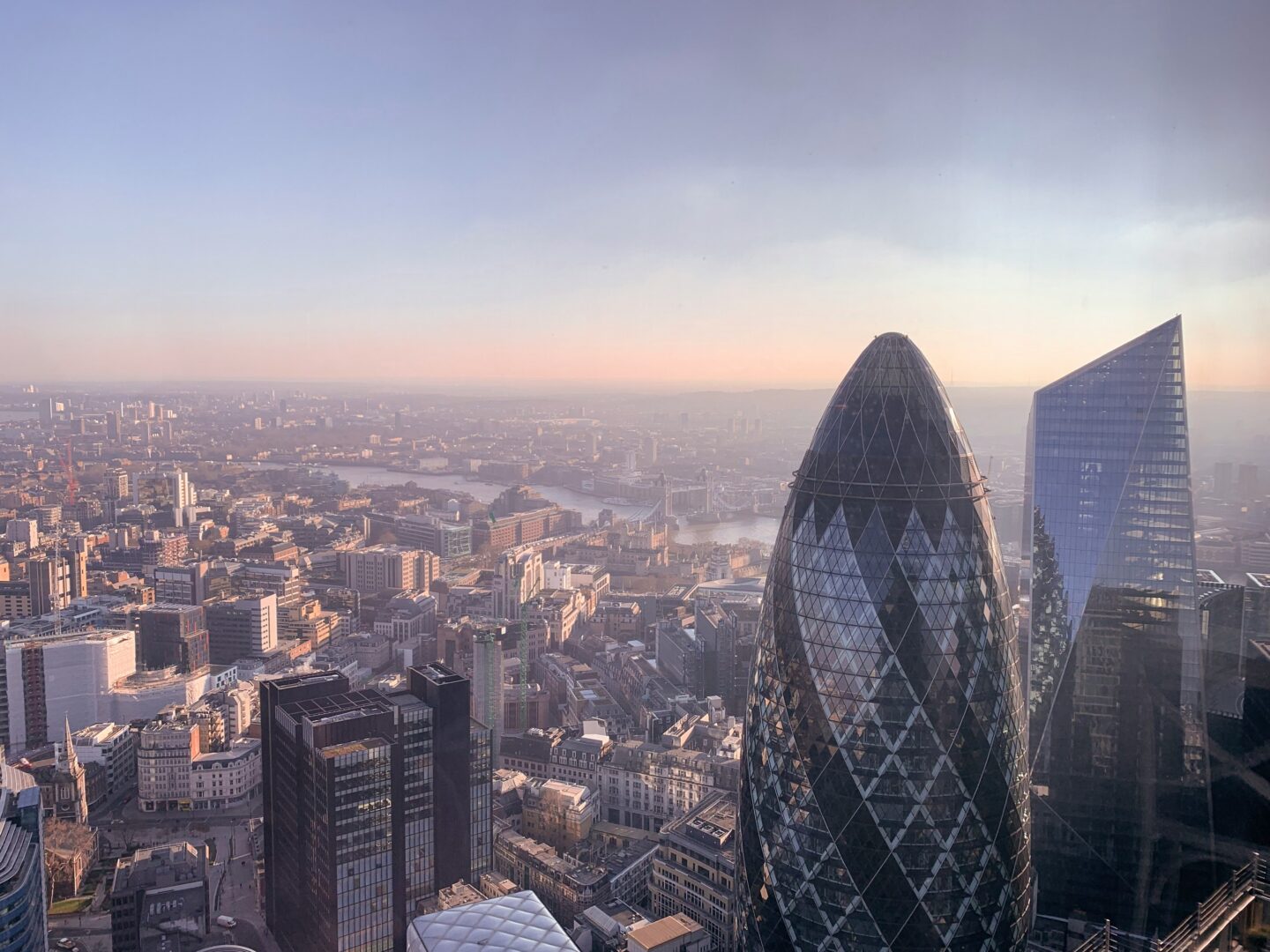 Aerial view of London skyline at sunset with the Gherkin and other modern skyscrapers.