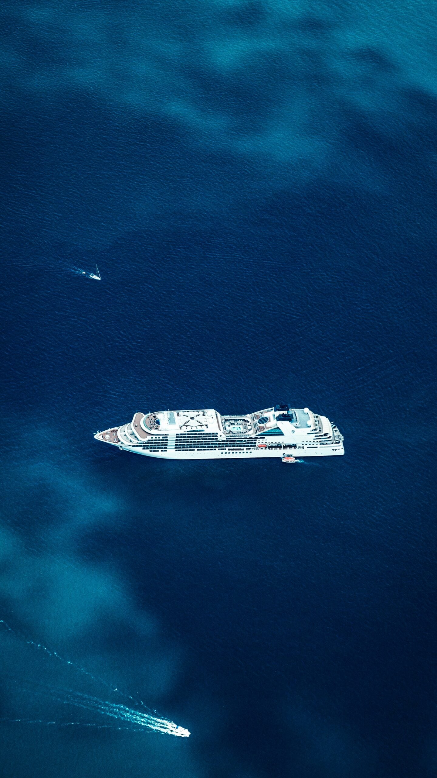 Aerial view of a luxury cruise ship sailing across deep blue ocean waters.