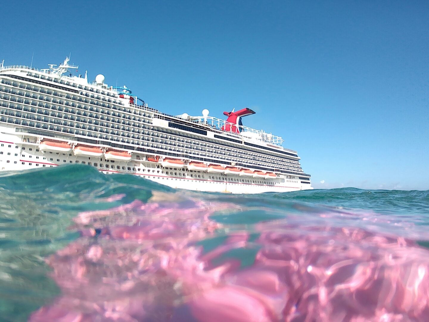 Cruise ship seen from the ocean with waves in the foreground on a sunny day.