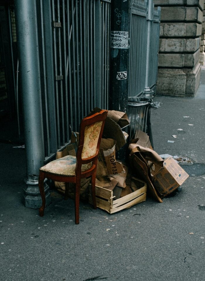 Old chair and piles of discarded cardboard boxes left on the street for junk removal and rubbish collection services.