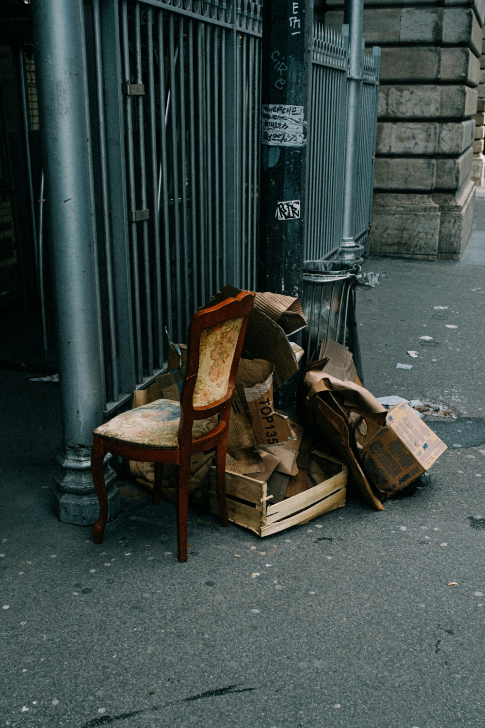Old chair and piles of discarded cardboard boxes left on the street for junk removal and rubbish collection services.