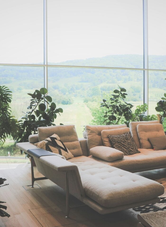 Bright upstairs living room with panoramic countryside views and lush indoor plants, showcasing upside-down home design for family flow.