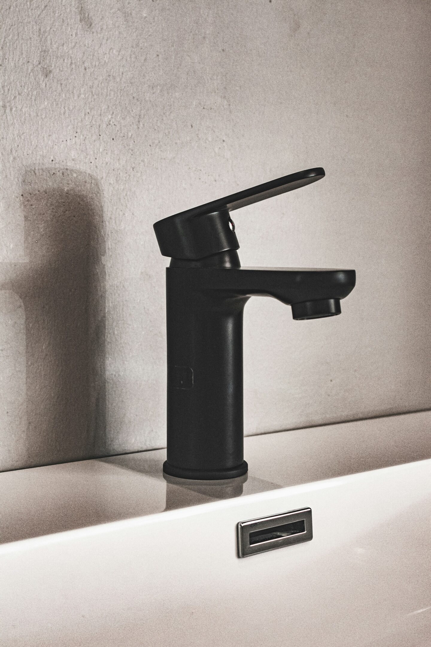 Close-up of a sleek matte black bathroom faucet on a white sink with a minimalist design.