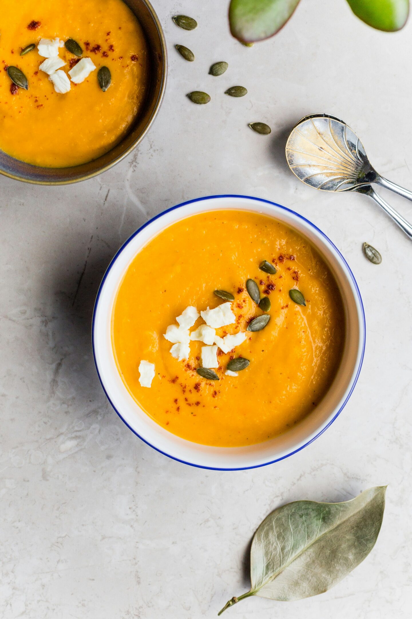 Bowl of creamy pumpkin soup garnished with feta cheese and pumpkin seeds, highlighting winter produce and comforting seasonal flavors.