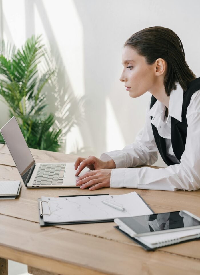 Professional woman working on a laptop in a bright modern office — focused accountant or entrepreneur planning business growth.