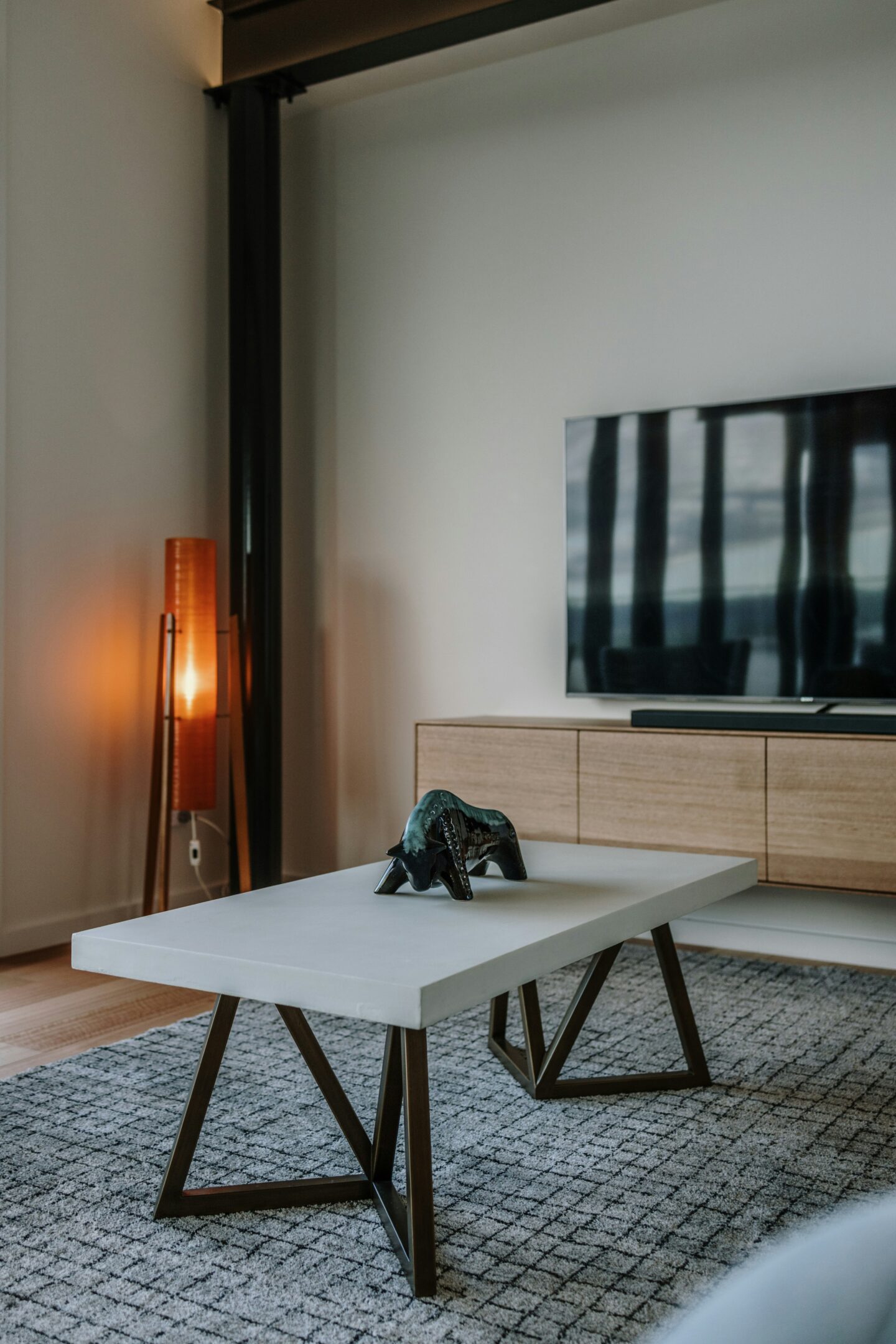 Minimalist living room with a modern coffee table, wooden TV stand, floor lamp, and neutral color palette.