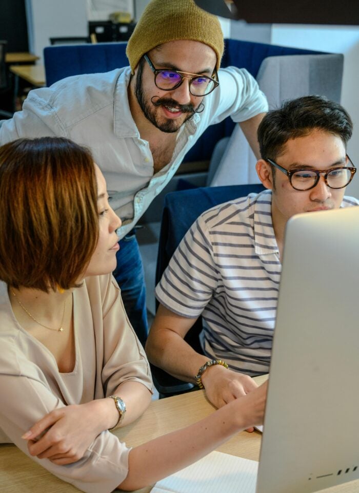 Startup team collaborating on financial strategy, discussing company valuation and selling startup shares on a computer in a modern office.