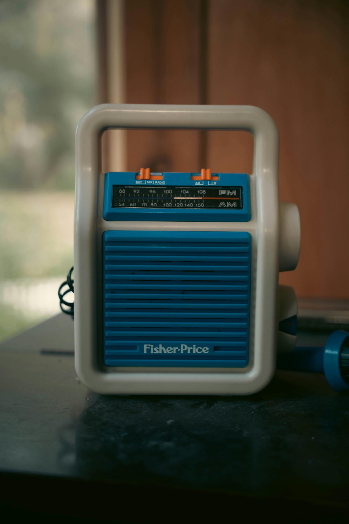 Close-up of a vintage Fisher-Price AM/FM radio with a blue front panel and white handle.