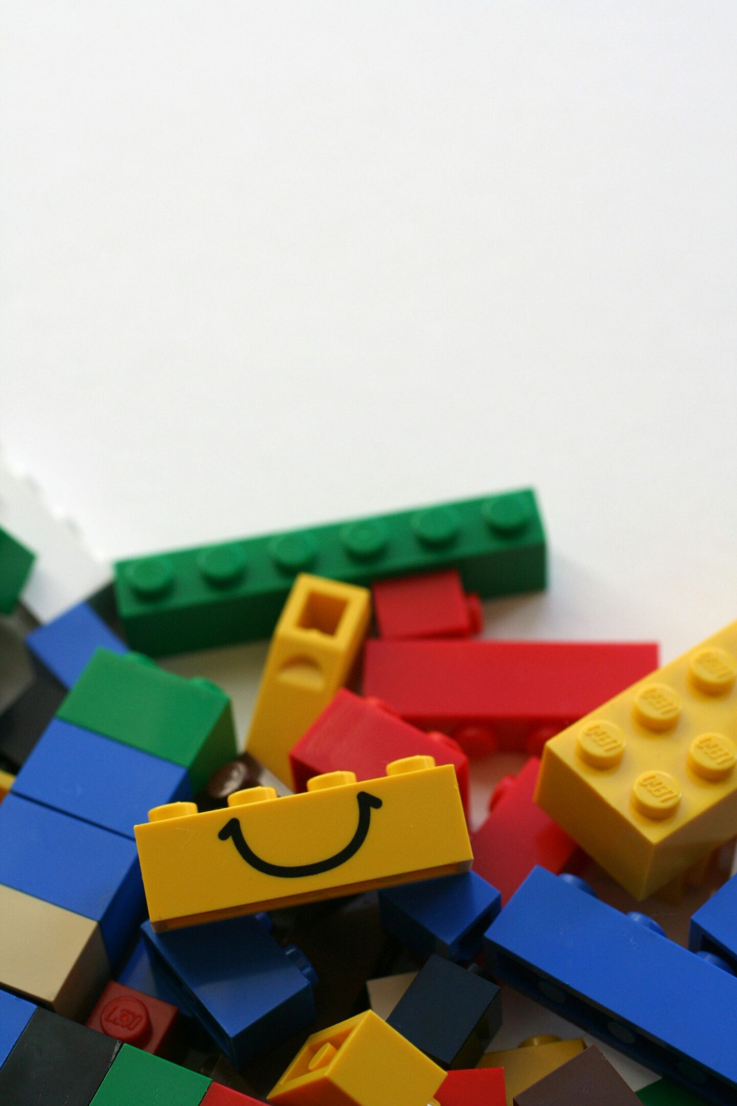 Colorful pile of LEGO bricks with a yellow block featuring a smiling face.