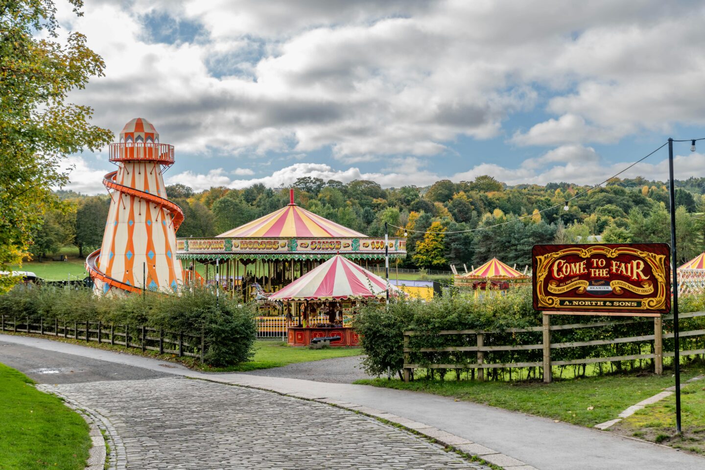 Traditional fairground with a helter-skelter and carousel at a countryside autumn fair in England.