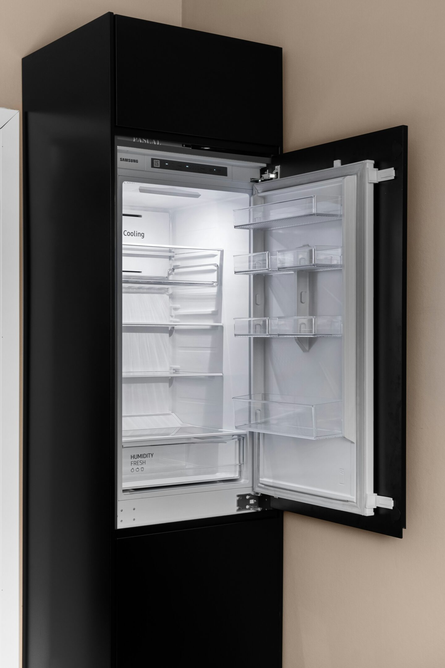 Modern black refrigerator with the door open, showing empty shelves and compartments inside.