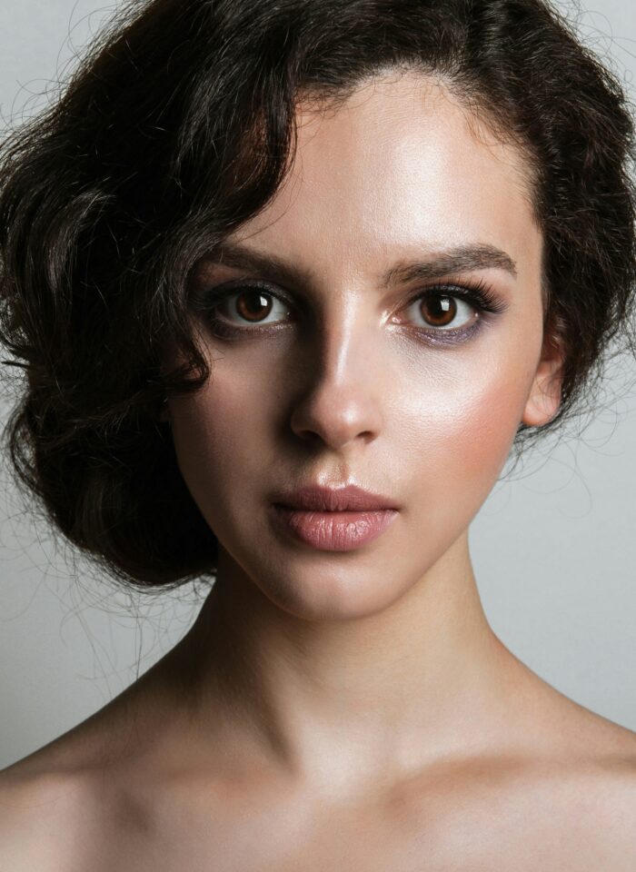Close-up portrait of a young woman with glowing skin, subtle makeup, and a smooth complexion, showcasing a youthful and refreshed look.