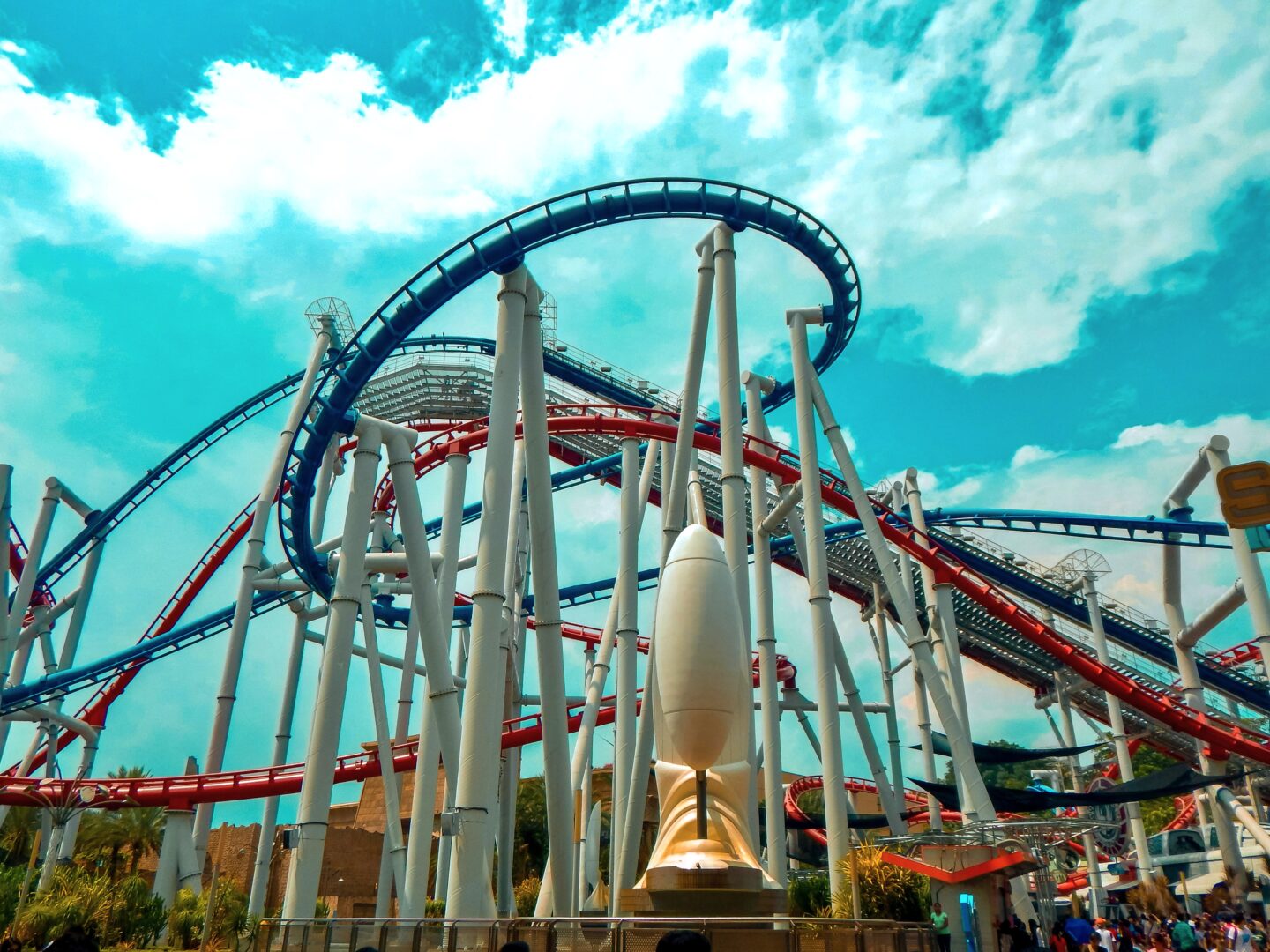 Twin-track red and blue roller coaster at Universal Studios Singapore under a bright blue sky.