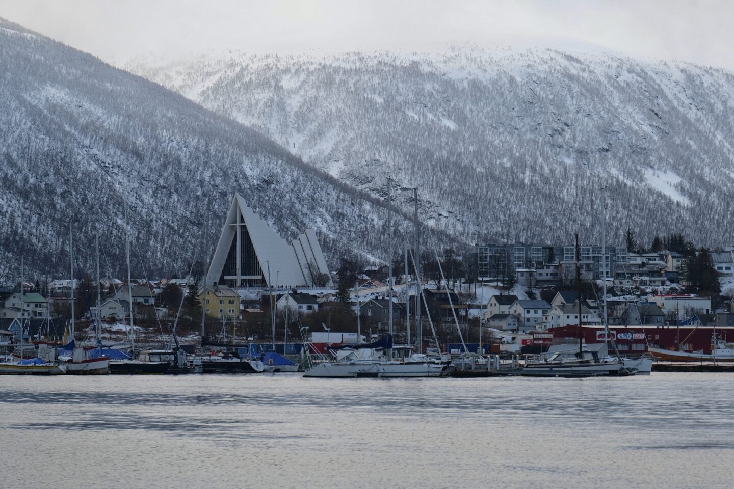Tromsø cityscape with Arctic Cathedral and snowy mountains reflected in the water, Norway