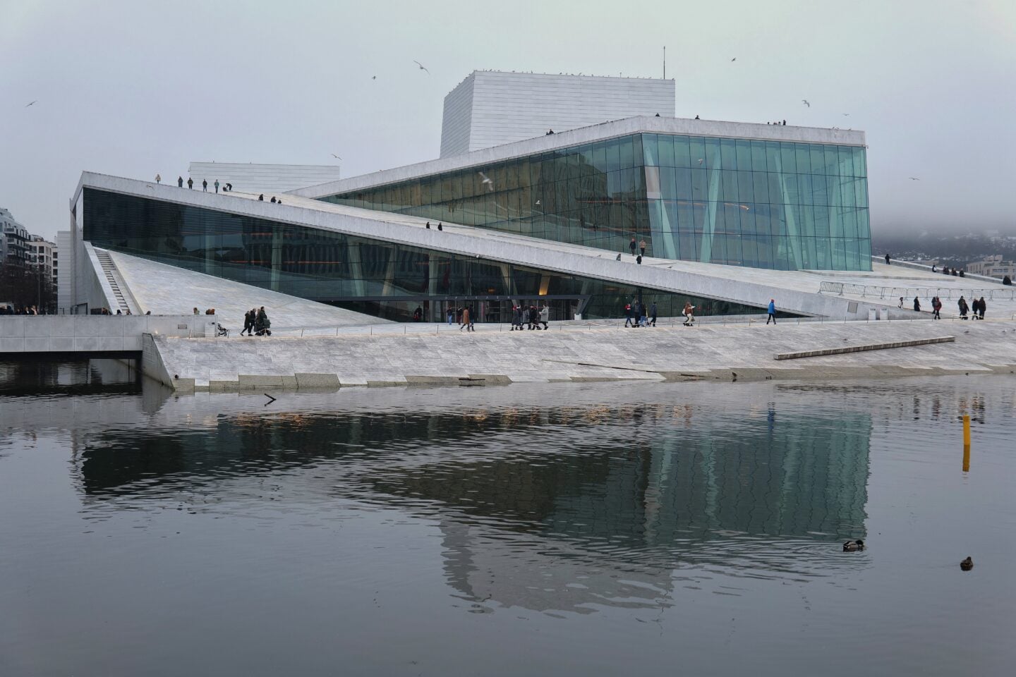 Modern Oslo Opera House with people walking along the waterfront, Oslo, Norway